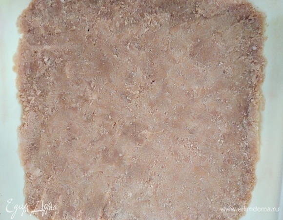 Форму для выпечки размером примерно 20х20 см смазать маслом (силиконовые не нужно смазывать). Распределить массу масла по форме, хорошо уплотняя руками или толкушкой для картофеля. Духовку разогреть до 180°C. Выпекать корж 5 минут.