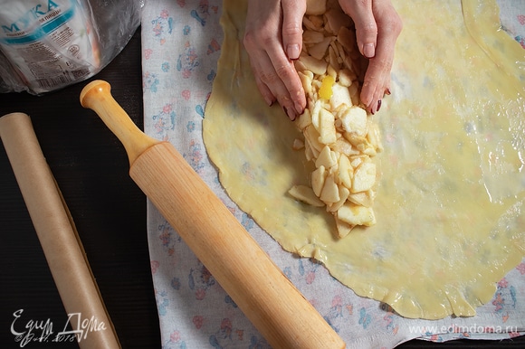 Растянуть тесто в прямоугольник, положить его узкой стороной к себе. Отступить треть от края и выложить яблочную начинку столбиком по длинной стороне.