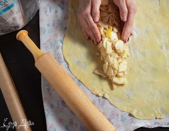 Растянуть тесто в прямоугольник, положить его узкой стороной к себе. Отступить треть от края и выложить яблочную начинку столбиком по длинной стороне.