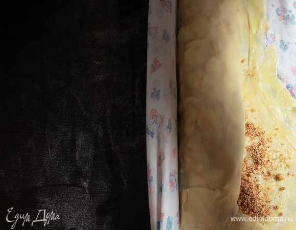 С помощью скатерти закрыть сначала узким краем, а потом постепенно свернуть рулетом, смазывая тесто маслом.