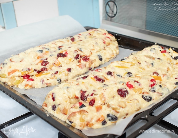 Выложить половину теста на противень, покрытый бумагой. Тесту придать форму вытянутой лепешки, похожей на лаваш. Ребром ладони отметить по длинной стороне треть от края. На большую часть положить колбаску марципана, накрыть меньшим краем. То же сделать со второй частью. Теперь придаем ему форму батона. Говорят, форма штоллена имеет символическое значение, она олицетворяет запеленатого младенца Христа. Готовые штоллены накрыть чистым полотенцем и оставить на расстойку минут на 40. Они должны увеличиться вдвое.