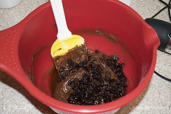 Добавить весь изюм и коньяк в шоколадное тесто, перемешать лопаткой.