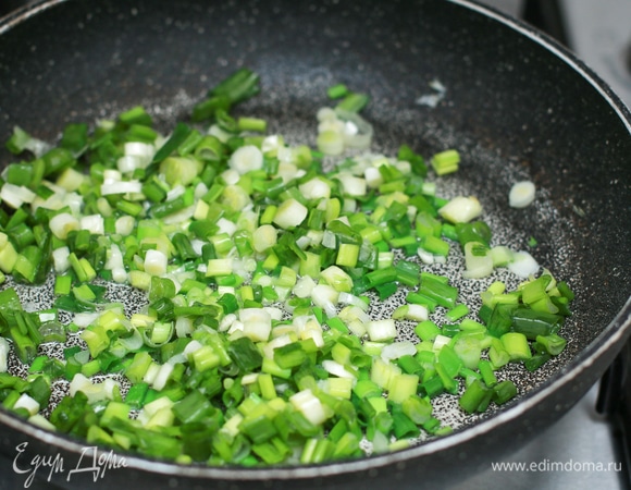 Приготовьте начинку. Для этого не очень мелко порубите всю зелень. В отдельной сковороде на очень медленном огне разогрейте растительное масло и сначала слегка потушите зеленый лук. Если нет зеленого лука, можно использовать репчатый, но его нужно будет потушить до полной прозрачности.