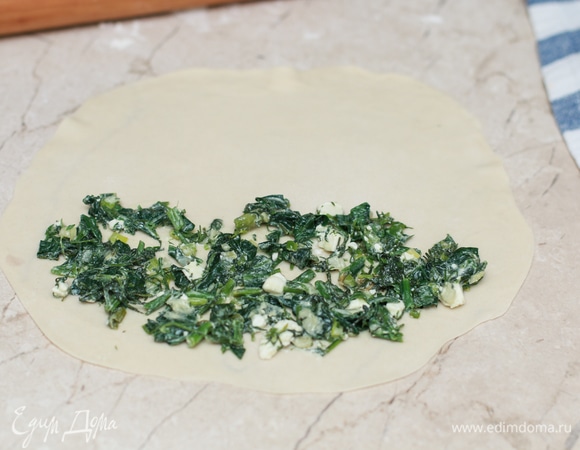 Каждый шар раскатайте в тонкий сочень. Выложите на одну половину примерно 1 ст. л. подготовленной начинки. Важно очень тонко раскатать тесто, не до прозрачности, но и не толще 2 мм. При необходимости подпыляйте тесто и стол мукой, чтобы тесто не прилипало.