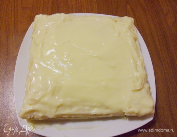 Теперь собираем торт. На тарелку положить одну половинку разрезанного коржа вогнутой стороной вверх. Сверху щедро смазать кремом.