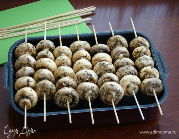 Маринованные грибочки нанизать на шпажки, смоченные водой, примерно штук по 5–6 и уложить на противень с высокими бортиками, создавая имитацию мангала. Запекать в разогретой до 200–210°C духовке минут 20.