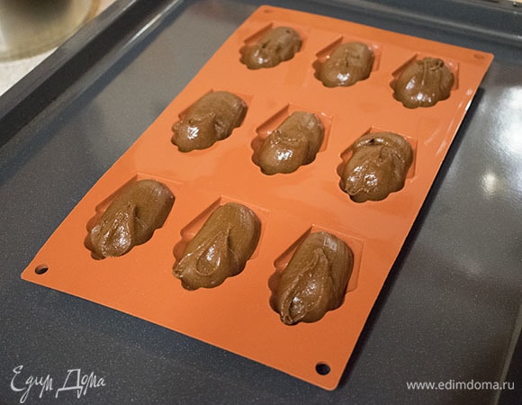 Отсадить тесто в формы. Если формы металлические, то предварительно смазать их сливочным маслом и посыпать мукой. Силиконовые формы смазывать не нужно. Можно использовать и обычные формы для маффинов, заполняя их на 1–1,5 см в высоту, если нет специальных форм.