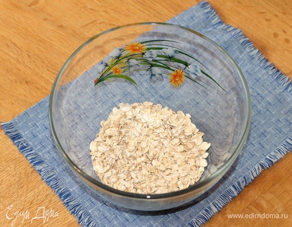 Овсяные хлопья высыпать в миску и залить горячим молоком, перемешать.