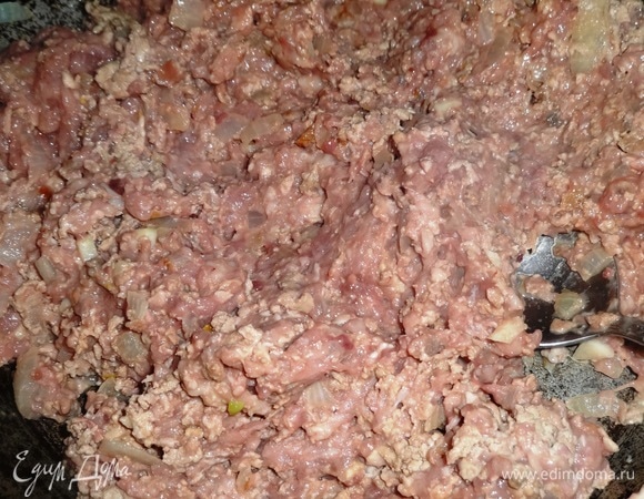 В сковороду с луком и чесноком выложить фарш и обжаривать до изменения цвета, периодически помешивая.