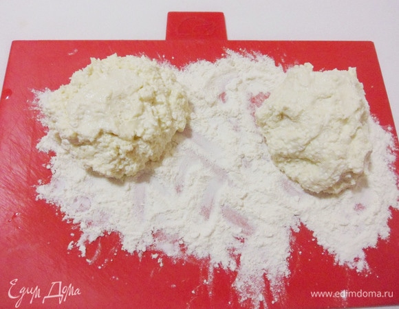 Посыпать рабочую поверхность мукой, выложить тесто и разделить его пополам.