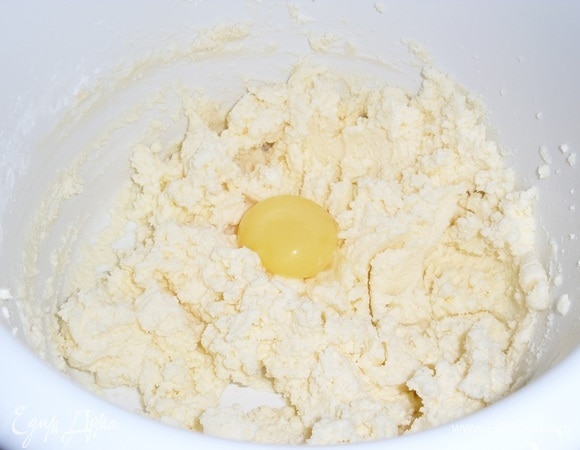 Подготавливаем продукты. Заранее достанем из холодильника сливочное масло и творог. Закладываем в чашу миксера творог, сливочное масло и сахарную пудру. Добавляем ванильный сахар и разрыхлитель. Хорошо взбиваем до пышности. Добавляем яичный желток. Взбиваем до однородного состояния.