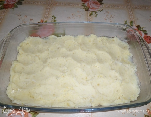 В смазанную форму выкладываем половину картофельного пюре. Равномерно распределяем.