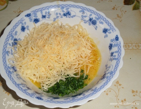 В чашку со взбитым яйцом добавляем половину натертого сыра и 2 щепотки нарезанной зелени. Перемешиваем.