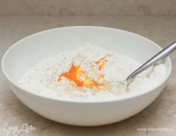 Разбейте яйцо, отделите желток от белка. Белок отложите для начинки, желток используется в тесте. В глубокую миску просейте муку, добавьте соль, желток и растительное масло.