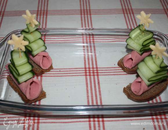 Для украшения из хлеба, колбасы, огурца и сыра сделать праздничные елочки.
