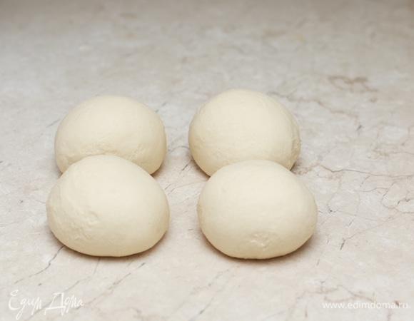 Разделите тесто на 4 части, придайте им форму шара и оставьте на 5 минут, накрыв кухонным полотенцем. После отдыха тесто будет легче раскатываться.