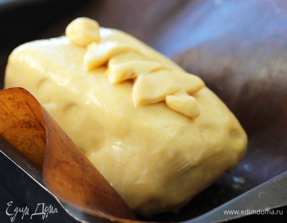 Переложить на раскатанное тесто. Свободные края смазать яйцом. Завернуть в конверт. Лишнее отрезать и хорошо защипнуть края. Переложить в форму, застеленную фольгой, швом вниз. Верх смазать желтком.