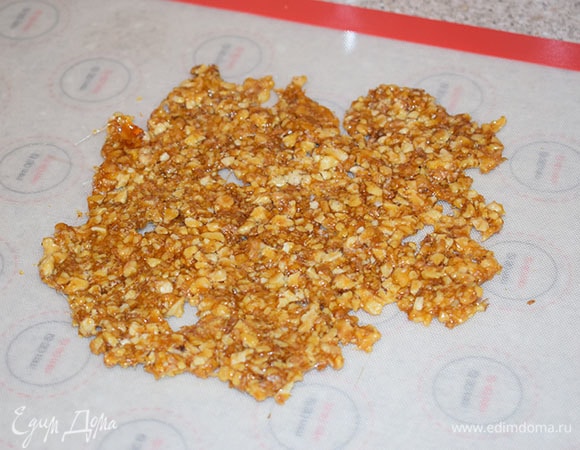 Добавить орехи в горячую карамель, перемешать. Выложить на силиконовый коврик и дать остыть.