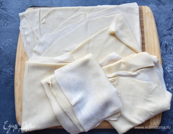 Отдохнувшее тесто разделить на четыре части. Каждую часть раскатать как можно тоньше. На рабочую поверхность выложить первый раскатанный лист теста и смазать его смальцем. Можно использовать мягкое сливочное масло. Сверху на слой жира уложить второй лист раскатанного теста и снова нанести слой жира. Таким образом использовать все тесто и смалец.