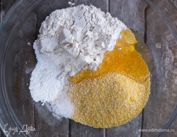Пока свиные отбивные маринуются, приготовьте кукурузный хлеб. Поместите в миску кукурузную и пшеничную муку. Добавьте мед, разрыхлитель и соль. Перемешайте.