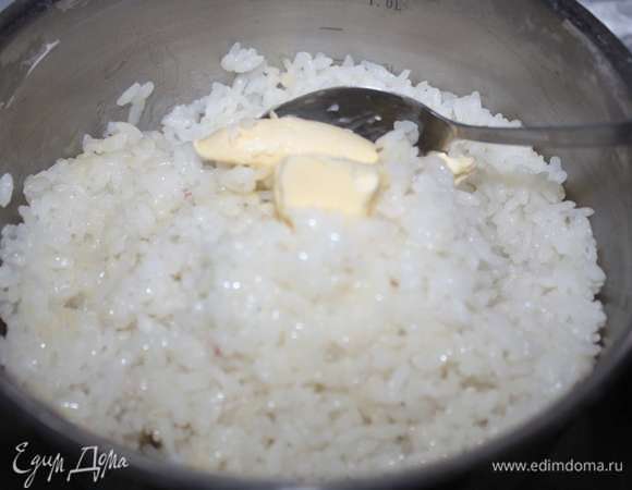 В горячий рис добавим сливочное масло и аккуратно перемешаем.
