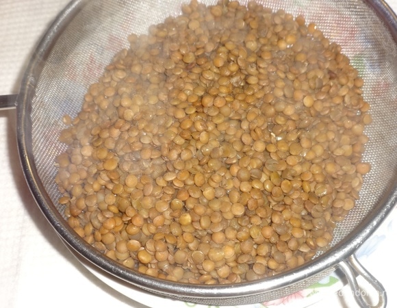 Отваренную чечевицу откинуть на сито, чтобы стекли остатки жидкости.