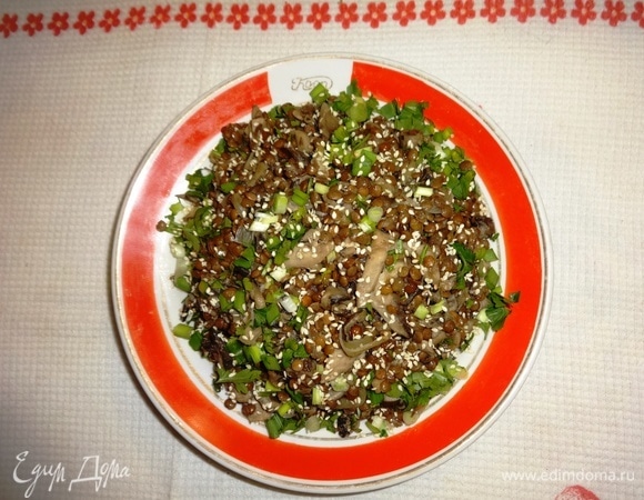 Выложить теплый салат из грибов и чечевицы на тарелку. Посыпать зеленью и обжаренным кунжутом.