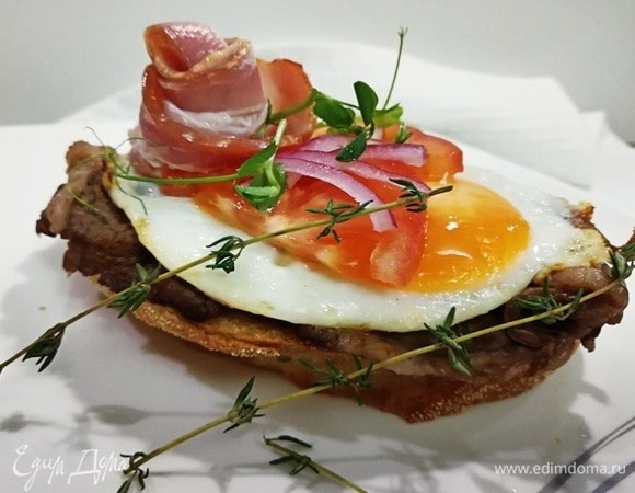 Украшаем тост ломтиками помидора, полукольцами лука и сырокопченым беконом.