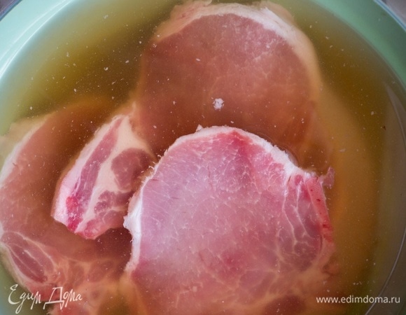 Сначала замаринуйте свиные отбивные. Налейте в миску воду, добавьте сахар, соль и перемешайте. Поместите в миску свиные отбивные и оставьте на 1 час.