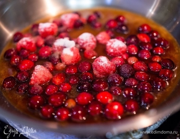 Теперь приготовьте ягодный соус. Налейте в кастрюлю вино и апельсиновый сок. Добавьте сахар и поставьте кастрюлю на огонь. Как только жидкость закипит, добавьте клюкву и малину. Я использовала замороженные ягоды, предварительно немного разморозив их.