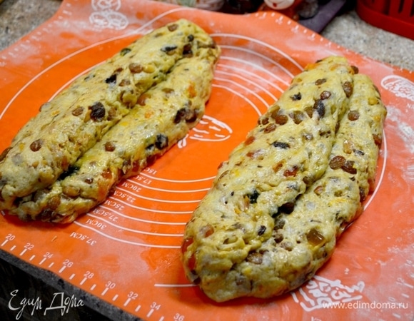 Формируем штоллен. Раскатываем в толстую лепешку тесто (я делала руками). Ладонью делаем углубление, оставляя одну часть немного больше, и на нее сверху кладем меньшую часть, получается как бы такой выступ. Накрываем полотенцем штоллены и расстаиваем 30 минут.