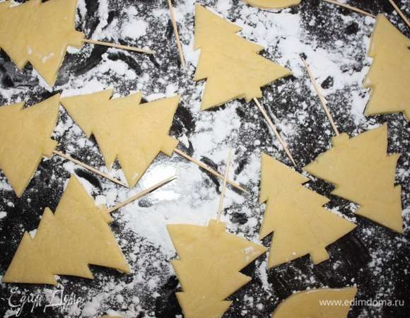 Вырезать из теста елочки и звездочки, вставить в них зубочистки.