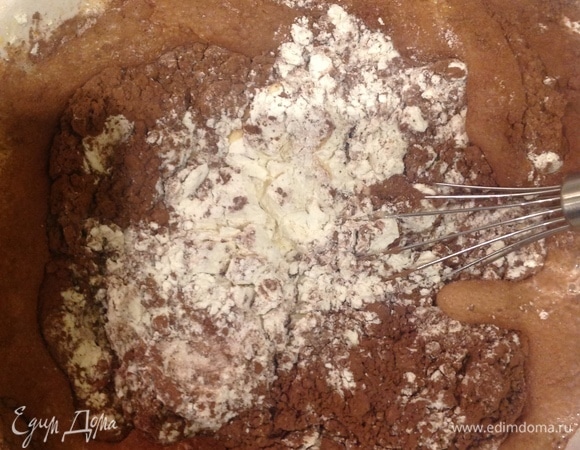 Включаю духовку на 180°C. Беру большую тарелку. Кладу муку, кефир, какао, гашу соду. Все перемешиваем миксером на маленькой скорости 2 минуты.