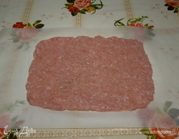 На столе расстилаем пергамент. Выкладываем мясной фарш. Равномерно распределяем в виде прямоугольника. Солим, перчим по вкусу.
