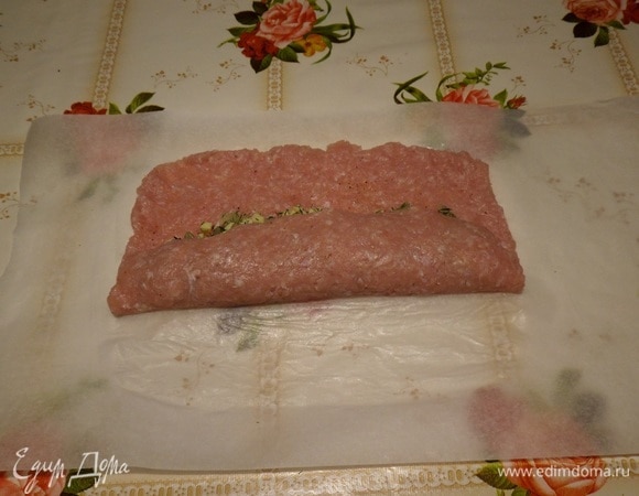 Приподнимаем край пергамента, накрывая начинку мясным фаршем.