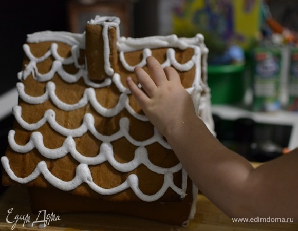 Глазурь перекладываем в полиэтиленовый пакет и срезаем кончик. Тщательно обрабатываем места склейки домика, чтобы скрыть следы карамели. Далее украшаем глазурью весь домик.