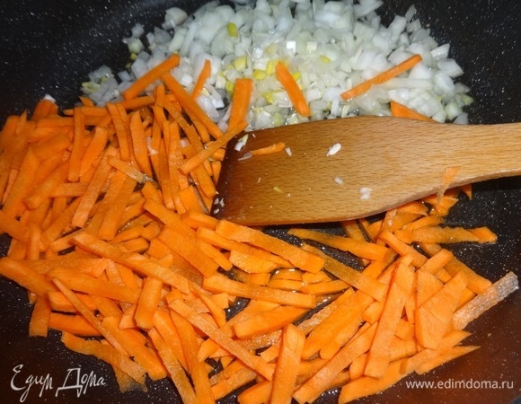 Выложить лук и морковь в сковороду с маслом от курицы и обжарить, помешивая, в течение нескольких минут.