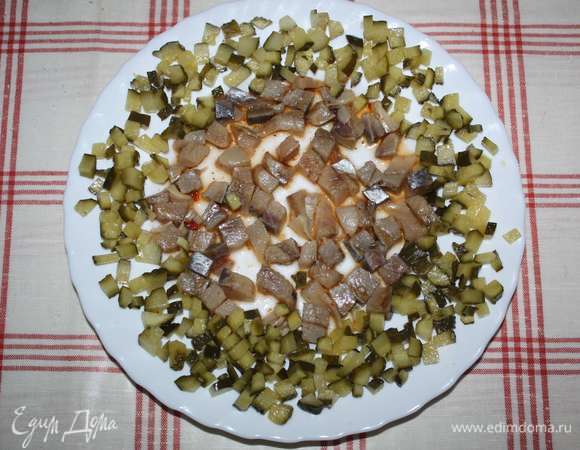 Маринованные огурцы нарезать кубиками, уложить вокруг селедки.