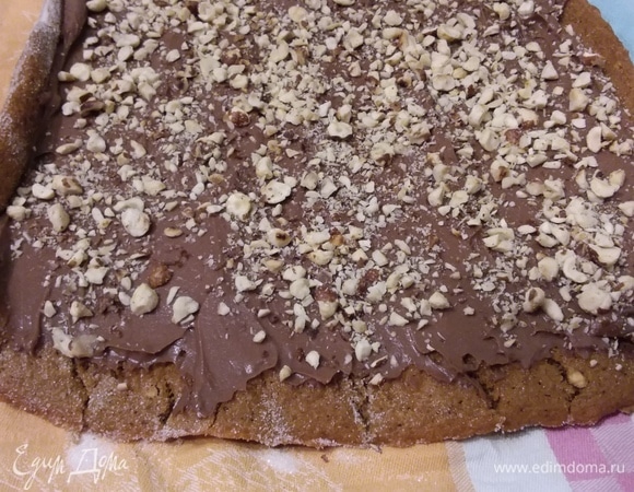 Посыпать орешками. Немного орешков оставить для декора. Свернуть в рулет.