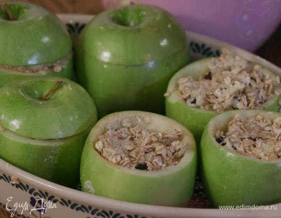 Яблоки поместить в жаропрочную керамическую форму, наполнить выемки овсяной смесью и накрыть крышечками.