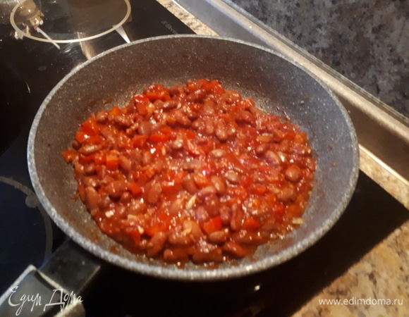 Обжаренные колбаски убрать из сковороды в другую посуду, обжарить в ней лук, затем добавить перец, обжарить, добавить чеснок. Далее открыть банку фасоли красной консервированной ТМ «Фрау Марта», слить сок, фасоль промыть, добавить к овощам. Затем добавить томатный сок и 1 ст. л. сахара. Потомить под крышкой минут 5.