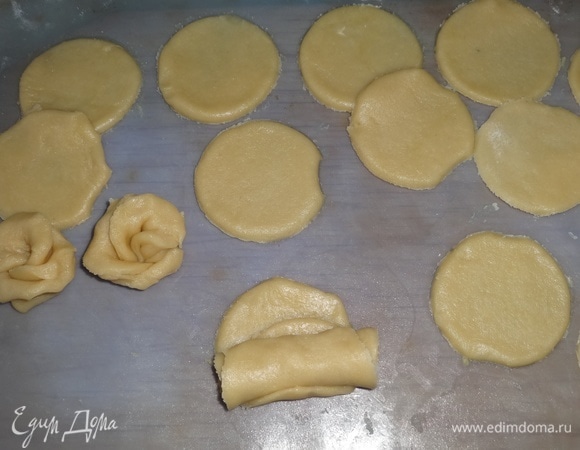 Повернуть кружки перпендикулярно к положению на предыдущем фото. Свернуть кружки в рулет, начиная от целого кружка и двигаясь к остальным. Заготовку разрезать пополам. У каждой части расправить лепестки, чтобы получились «розы».