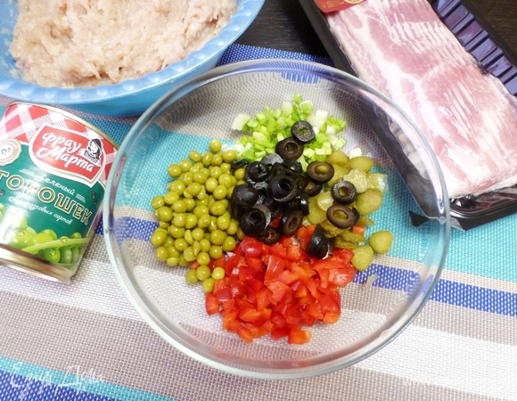 Приготовить наполнитель для террина. С консервированного горошка ТМ «Фрау Марта» слить жидкость. Маслины и маринованные корнишоны нарезать колечками, сладкий перец — мелким кубиком и измельчить зеленый лук.