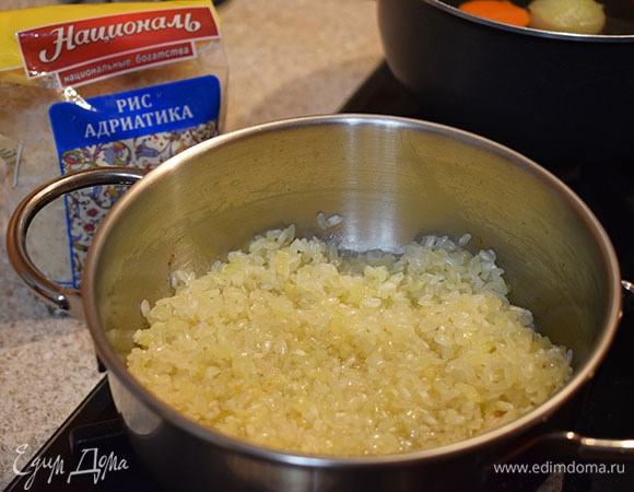 Влить вино в рис. Продолжать мешать, пока вино полностью не впитается.