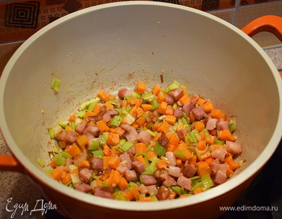 Добавить в кастрюлю морковь, лук-порей, лук репчатый и чеснок. Обжарить до золотистого цвета.