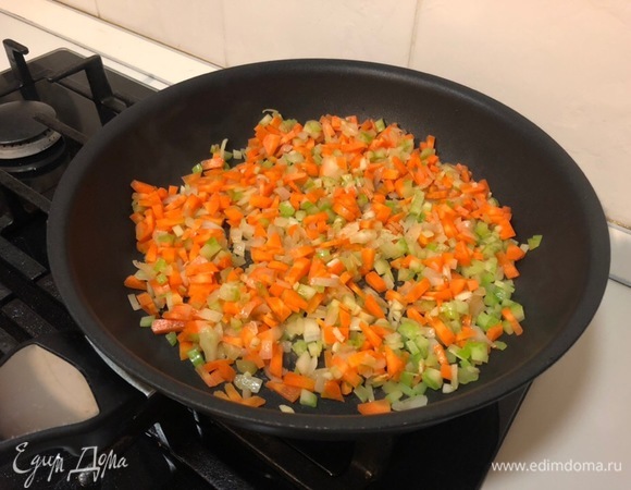 После добавляем остальные овощи — морковь и один стебель сельдерея. Перемешиваем, убавляем огонь до минимума и тушим минут 15 до мягкости овощей.