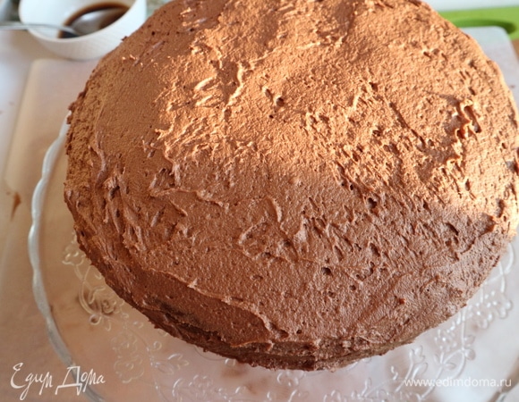 Третий корж с внутренней стороны пропитать приготовленной смесью. Поместить его на второй корж. Смазать трюфельными сливками. Смазать борта трюфельными сливками.