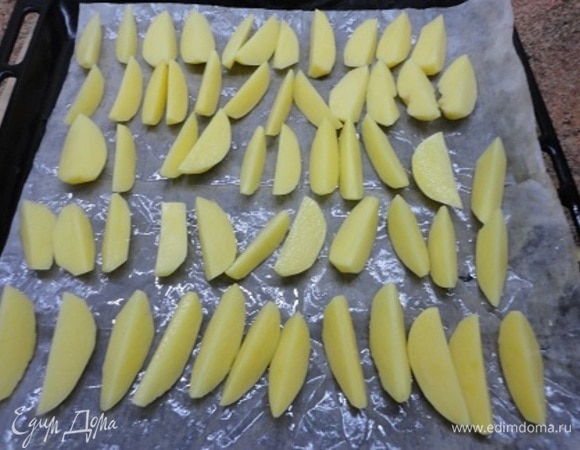 Очищенный и нарезанный дольками картофель выкладываем на смазанный маслом лист, не солим. Запекаем в духовке до готовности.