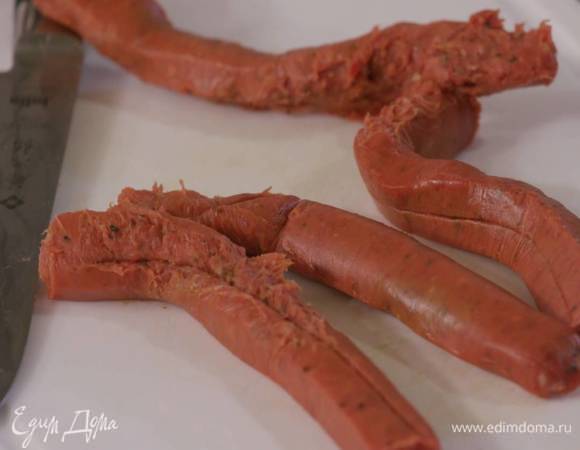 Колбаски надрезать вдоль и, сняв верхнюю оболочку, порезать, затем отправить в кастрюлю с овощами и обжарить.