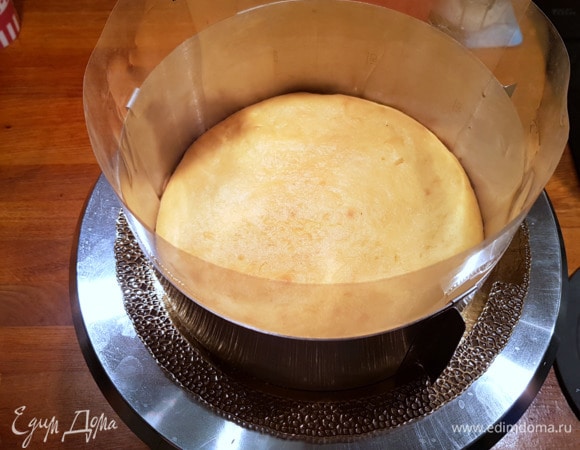 Так как дальнейшие действия будут в очень скором темпе, перед приготовлением итальянской меренги подготовим основу для сборки торта. Для этого берем подложку (если ее нет, то просто сервировочное блюдо). Укладываем нижний корж большего диаметра (20 см). Далее устанавливаем форму для сборки — этот пункт обязательный, без формы торт не собрать. Форма не обязательно должна быть круглой формы. Далее укрываем бока ацетатной пленкой. Если ее нет в вашем арсенале, то можно использовать плотный пергамент. На этом этапе подготовка закончена, переходим к приготовлению меренги.